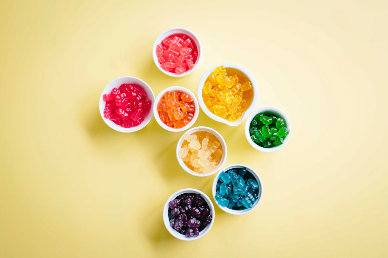 Gummy bears sorted by color into white tasting bowls