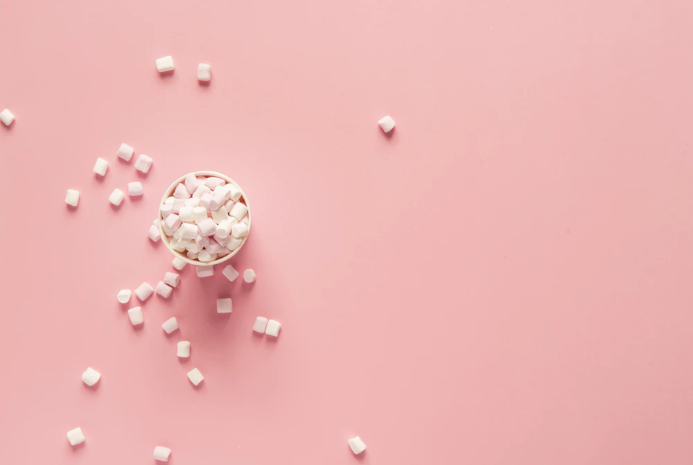 White marshmallows in a bowl on a pink background